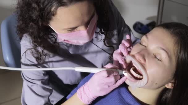 Dentista haciendo limpieza dental profesional mujer joven paciente en el consultorio dental. Plan de primer plano — Vídeos de Stock