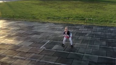 Genç bir kadın yazın stadyuma silgiyle spor yapmaya gider..