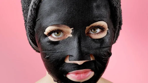 Young Woman Apply Black Cosmetic Fabric Facial Mask Pink Background — Stock Photo, Image