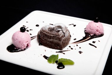 Tatlı fondan çikolata siyah bir zemin üzerine beyaz bir plaka üzerinde dondurma ile. Enfes Fransız çikolata tatlı fondan.