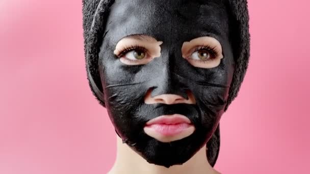 Mladá Žena Aplikovat Černé Kosmetické Tkaniny Obličejové Masky Růžovém Pozadí — Stock video