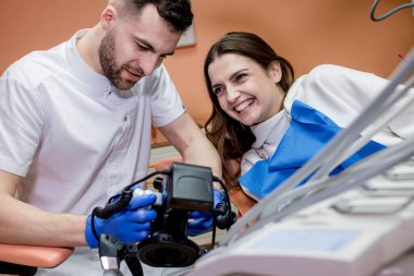 Diş hekimi hastaya tedavinin sonucunun bir resmini gösterir. Memnun hasta..