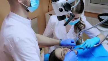 Dişçi mikroskopla hastanın dişlerine bakıyor. Modern ilerici dişçilik.