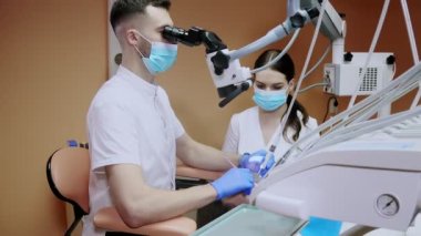Dişçi mikroskopla hastanın dişlerine bakıyor. Modern ilerici dişçilik.