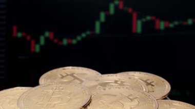 Birçok altın bitcoin bir ticaret grafiği ile arka planda döner. fiziksel bitcoin, dijital para birimi, şifreleme para birimi, btc.