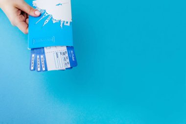 Mavi arka planda kadın el pasaport ve uçak bileti. Seyahat konsepti, kopya alanı.