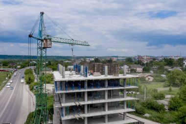 İşçiler, modern binanın büyük inşaat sahasında vinç ve çelik beton takviyesi ile çalışıyorlar. Modern monolitik endüstriyel yapı.