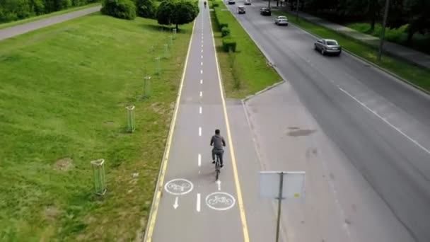 Um jovem monta uma bicicleta em um caminho de bicicleta em um dia ensolarado. Treinamento atlético ou treinamento de força em um dia ensolarado de verão. Estilo de vida de ciclismo saudável — Vídeo de Stock