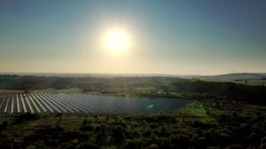 Gün batımında bir tarlada bulunan devasa bir fotovoltaik güç istasyonunun üst görüntüsü. Güneş enerjisi santrali. Ekolojik temiz enerji. Alternatif güneş istasyonu.