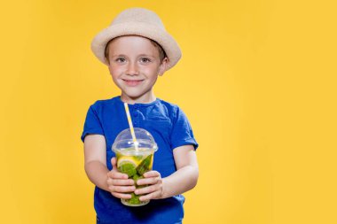 Yaz içeceği. Soğuk içecek. Elinde bir bardak taze limonata olan küçük bir çocuk..