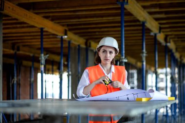 Şablon planıyla inşaat alanının içinde çalışan, gezinen mimar veya mühendis.