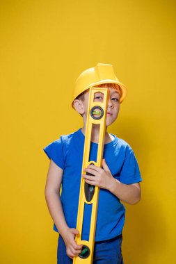 Sarı kask takan, düzgün aletli küçük çocuk..