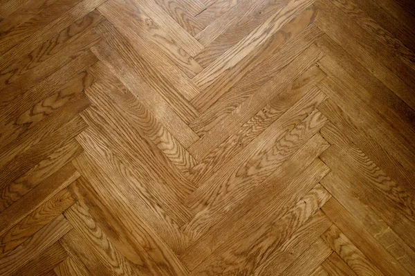 Classic wooden oak parquet in the form of a dark brown Christmas tree. Brown seamless parquet floor with a pattern of spruce from narrow boards.