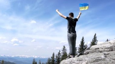 Vatansever adam dağın zirvesinde Ukrayna bayrağı sallıyor. Savaşın zaferini kutluyoruz..