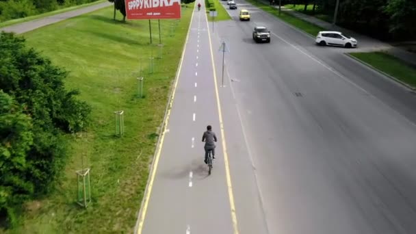 Um jovem monta uma bicicleta em um caminho de bicicleta em um dia ensolarado. Treinamento atlético ou treinamento de força em um dia ensolarado de verão. Estilo de vida de ciclismo saudável — Vídeo de Stock