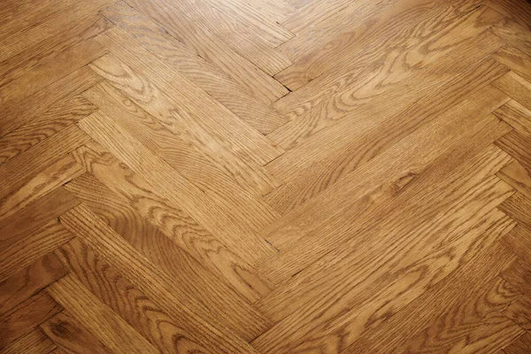 Classic wooden oak parquet in the form of a dark brown Christmas tree. Brown seamless parquet floor with a pattern of spruce from narrow boards.