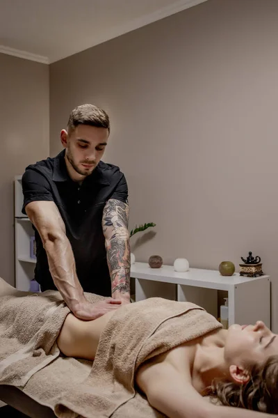 Giovane donna con massaggio addominale. Il massaggiatore fa il massaggio per stomaco — Foto Stock