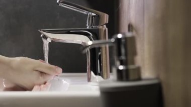 Kadın şeker kutusunu itiyor ve sıvı sabun eline sıkışıyor. Kadınlar tuvalette ellerini yıkamak için gelişmiş cilt bakımı ve dezenfeksiyon için hafif bir jel kullanıyor..