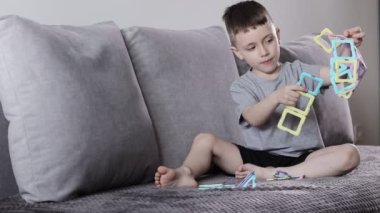 Manyetik inşaatçıyla oynayan küçük bir çocuk. Yaratıcılık gelişimi. Manyetik yapıcı.