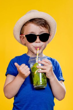 Sarı Stüdyo Üzerindeki Plastik Kupa 'dan Mojito kokteyli içen tatlı çocuk..