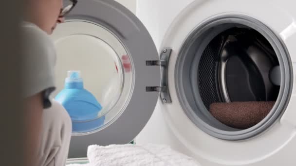 女性は洗濯機に洗濯粉のカプセルを入れます 洗濯機に汚れた洗濯機をロードします 現代の液体洗剤 — ストック動画