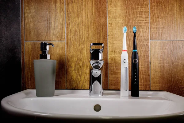 Duas Escovas Dentes Elétricas Pia Banheiro Com Dispensador Sabão Cinza — Fotografia de Stock