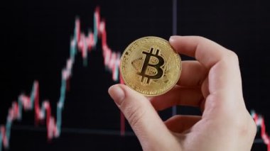 Arka planda, btc 'nin borsa tablosu üzerinde Bitcoin tutan kadın..