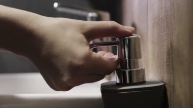 Kadın şeker kutusunu itiyor ve sıvı sabun eline sıkışıyor. Kadınlar tuvalette ellerini yıkamak için gelişmiş cilt bakımı ve dezenfeksiyon için hafif bir jel kullanıyor.