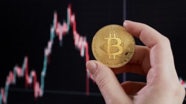 Arka planda, btc 'nin borsa tablosu üzerinde Bitcoin tutan kadın.