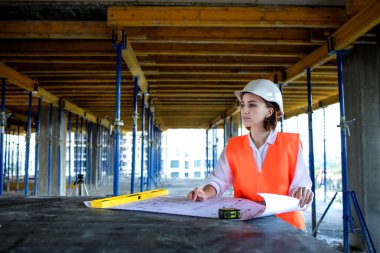 Şablon planıyla inşaat alanının içinde çalışan, gezinen mimar veya mühendis.