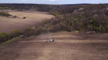 Havadan bakıldığında büyük bir traktör kuru bir alan oluşturuyor. Yukarıdan aşağıya traktör, toprağı işliyor ve kuru bir tarla ekiyor. Hava traktörü, tarla ekimi için çayırları kesiyor