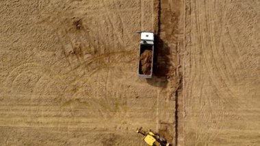 Sarı kazıcı zemini kazar ve bir kamyona yükler. Üst görünüm.