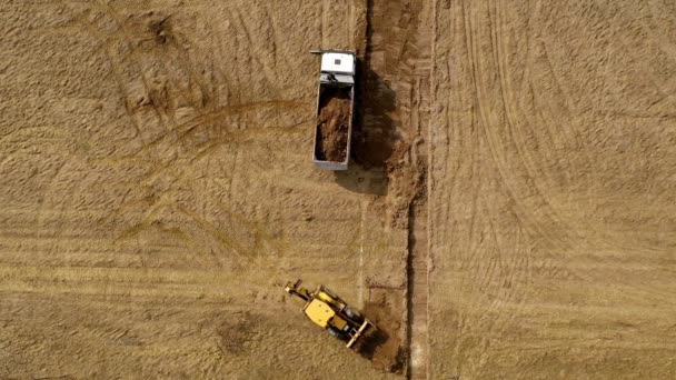 Żółty Koparka Kopie Ziemię Ładuje Ciężarówkę Widok Góry — Wideo stockowe