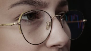 Genç kadının yüzünü ve bilgisayar grafiklerini gözlüklerle kapat. Kadın bilgisayardaki dijital değiş tokuş üzerinde Bitcoin fiyat grafiğini kontrol ediyor, kripto para birimi gelecekteki fiyat öngörüsü.