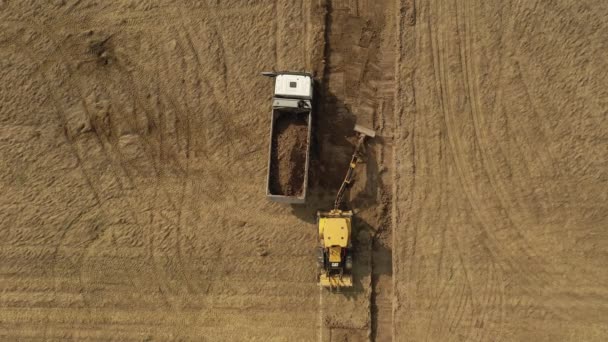 黄色的挖掘机把地面挖开 装上卡车 顶部视图 — 图库视频影像
