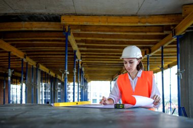 Şablon planıyla inşaat alanının içinde çalışan, gezinen mimar veya mühendis.