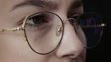 Genç kadınların yüzlerini ve bilgisayar grafiklerini gözlüklerle kapatın. Kadın bilgisayardaki dijital değiş tokuş üzerinde Bitcoin fiyat grafiğini kontrol ediyor, kripto para birimi gelecekteki fiyat öngörüsü.