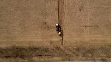 Sarı kazıcı zemini kazar ve bir kamyona yükler. Üst görünüm.