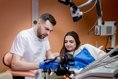 Diş hekimi hastaya tedavinin sonucunun bir resmini gösterir. Memnun hasta..