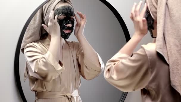 Ung Lycklig Kvinna Handduk Gör Ansiktsmask Och Tittar Spegel Elegant — Stockvideo