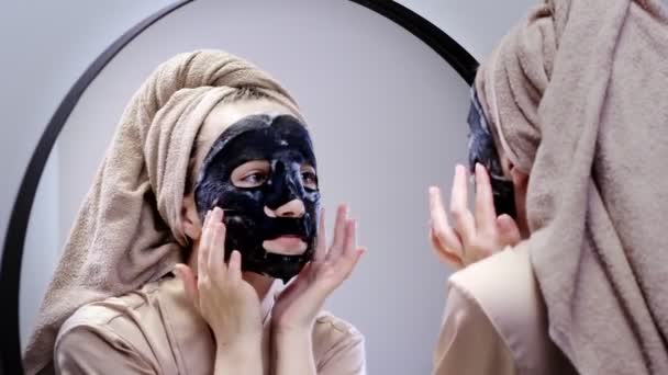 Wanita Muda Dengan Handuk Bermasker Wajah Dan Bercermin Kamar Mandi — Stok Video