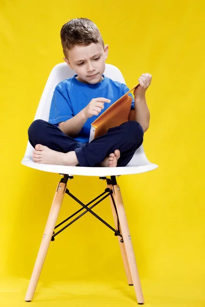 5岁至6岁的小可爱的金发绿眼睛男孩 穿着时髦的蓝色T恤 拿着书 阅读着黄色墙壁的背景图片和孩子们的工作室肖像 — 图库照片