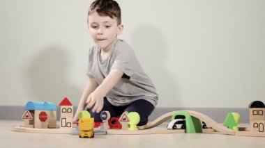 Sevimli çocuk ahşap trenle oynuyor, onu köprüden karşıya uçuruyor. Ahşap eğitim oyuncakları.