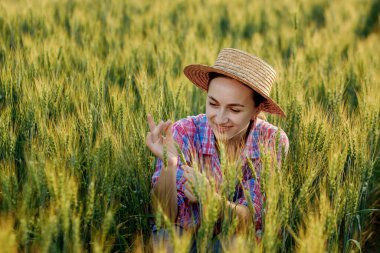 Kareli gömlekli genç bir çiftçi buğday başağında oturur ve hasatta sevinir..