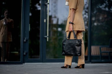 İş kadını elinde laptop çantasıyla ofise gidiyor. Şehirdeki modern binalarda iş kadını görüntüsü.