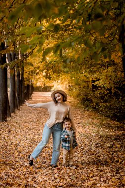 Güneşli bir sonbahar gününde anne ve oğlu dışarıda yürüyor. Aile sonbahar giysileri giyiyor. Birlikte mutluyuz.