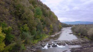 Mountain river with cold clear water. The river flows over the stones with little waterfall.