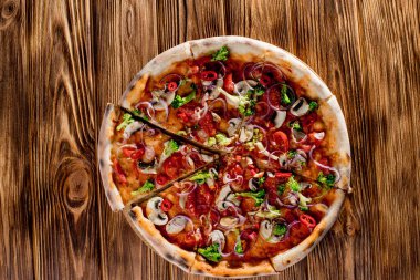 Vegan pizza with tomato sauce, cherry tomatoes, mushrooms, broccoli, red onion on wodenbackground. View from above.