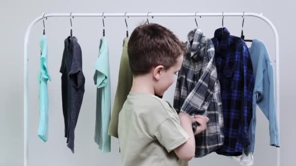 Anaokulu Çocuğu Askıların Yanında Duruyor Elbiselerini Diziyor Bugün Için Kıyafet — Stok video