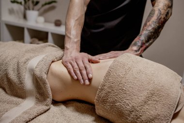 Kaplıcadaki kadına mide masajı yapan bir terapist..